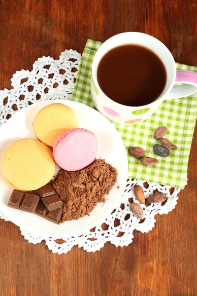 Kakao v šálku s sladkosti a kakaový prášek na štítku na dřevěný stůl — Stock fotografie