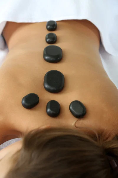 Hermosa mujer joven teniendo masaje de piedra en el salón de spa —  Fotos de Stock