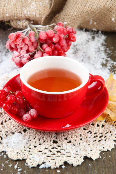 Still life with viburnum tea in cup, berries and snow, on wooden background — Stock Photo, Image