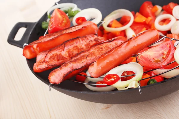 Heerlijke worstjes met groenten in de wok op houten tafel close-up — Stockfoto