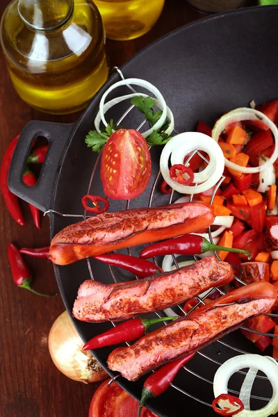 Delicious sausages with vegetables in wok on wooden table close-up — Stock Photo, Image