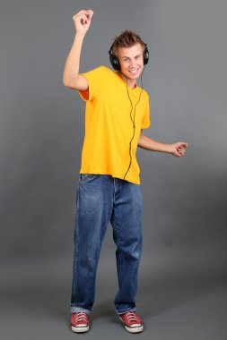 yakışıklı genç adam gri arka planda müzik dinlemek