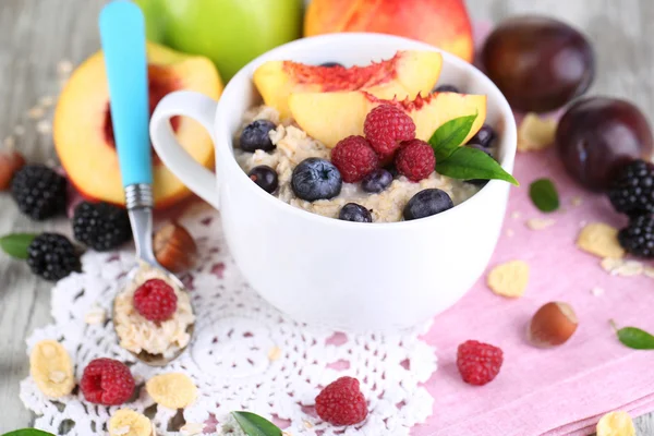 Oatmeal in cup with berries on napkins on wooden table — Stock Photo, Image