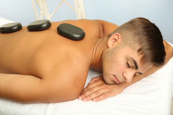 Jonge man ontspannen met hete stenen op rug voordat massage — Stockfoto