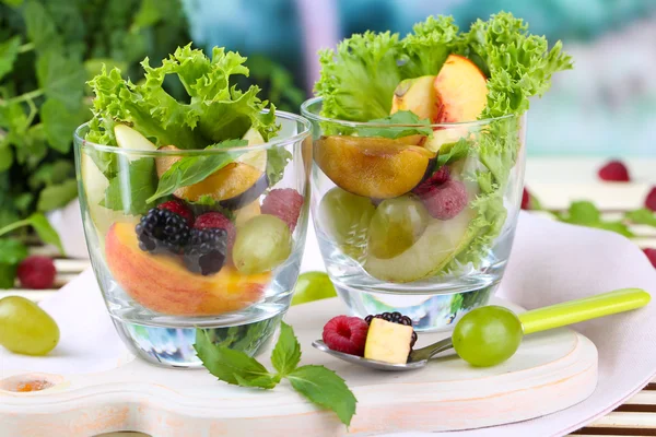 Obstsalat im Glas, auf Holztisch, auf hellem Hintergrund — Stockfoto