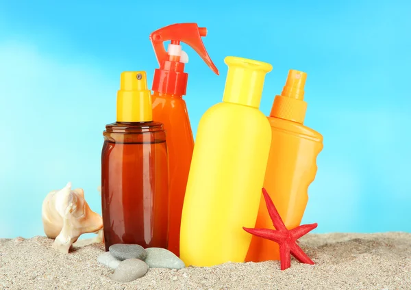 Bottles with suntan cream, on blue background — Stock Photo, Image
