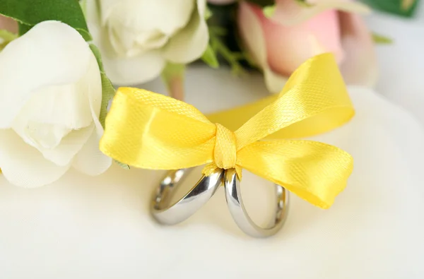 Wedding rings tied with ribbon on white fabric — Stock Photo, Image