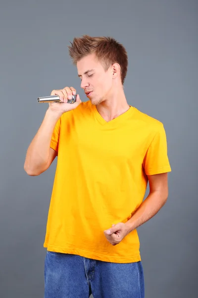 Knappe jonge man zingt op grijze achtergrond — Stockfoto