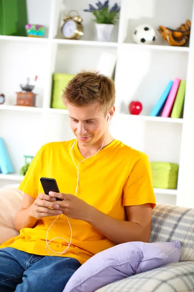 Ung man koppla av på soffan med mobiltelefon — Stockfoto