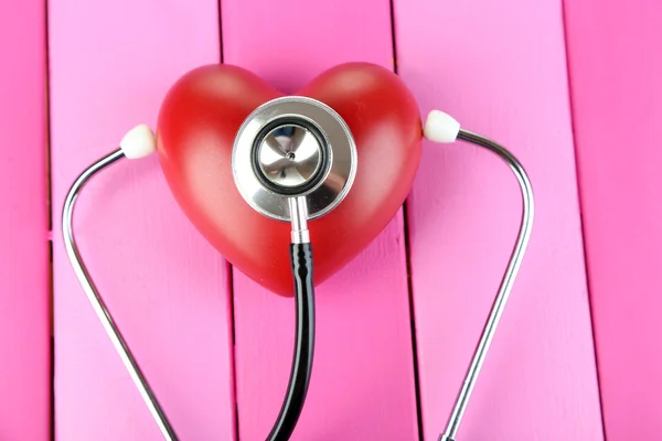 Stethoscope and heart on wooden table close-up — Stock Photo, Image