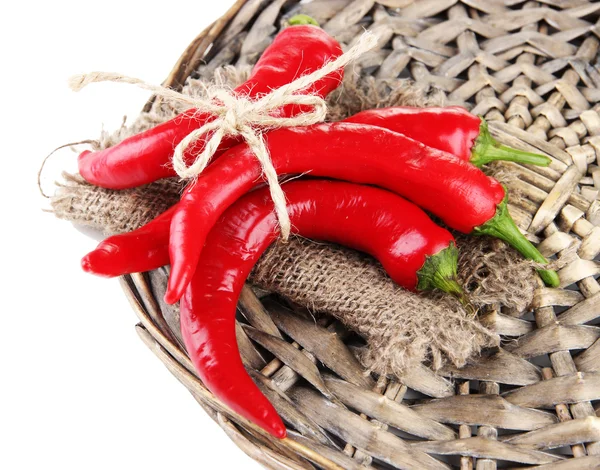 Red hot chili peppers on wicker mat, isolated on white — Stock Photo, Image