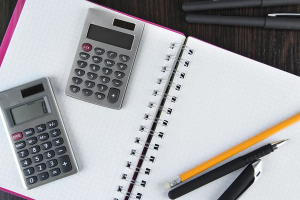 Cuaderno con bolígrafos, lápiz y calculadoras de cerca — Foto de Stock