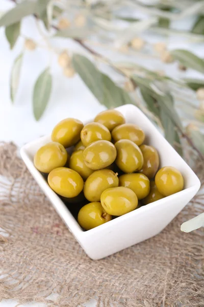 Olive in ciotola con ramo su sacco da vicino — Foto Stock