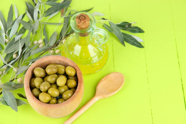 Olivolja gren och olivolja i skål på träbord — Stockfoto