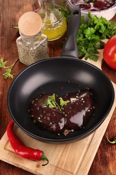 Raw liver in pan with spices and condiments on wooden table close-up — Stock Photo, Image