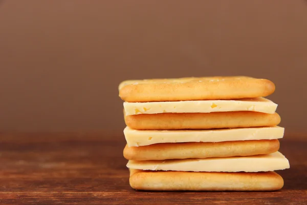 Läckra kex med ost på träbord på brun bakgrund — Stockfoto