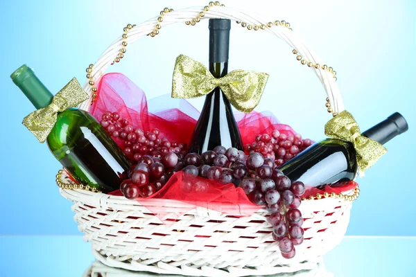 Gift basket with wine on blue background — Stock Photo, Image