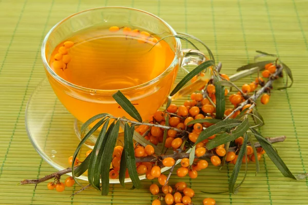 Branches of sea buckthorn with tea on bamboo background — Stock Photo, Image