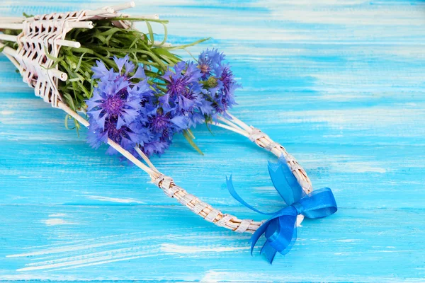 Beautiful bouquet of cornflowers in basket on blue background — Stock Photo, Image