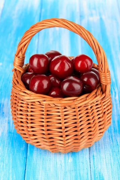 Kirschbeeren im Weidenkorb auf Holztisch in Großaufnahme — Stockfoto