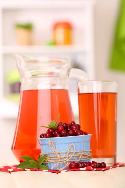 Džbán a sklenice brusinkové šťávy s červenými brusinky na stole — Stock fotografie