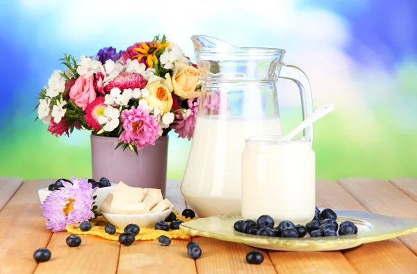 Produtos lácteos frescos com mirtilo em mesa de madeira sobre fundo natural — Fotografia de Stock