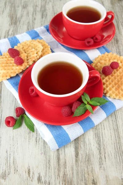 Tazas de té con galletas y frambuesas en primer plano de la mesa — Foto de Stock