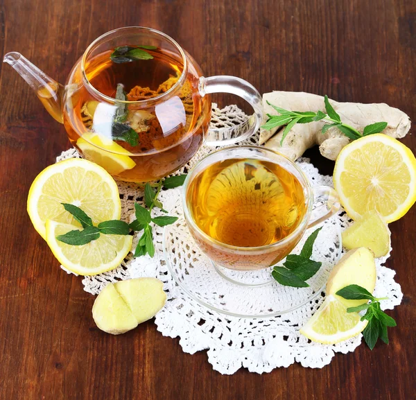 Chaleira e xícara de chá com gengibre no guardanapo na mesa de madeira — Fotografia de Stock
