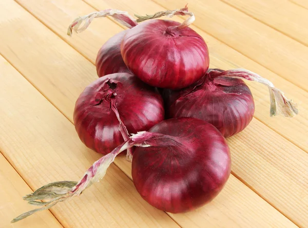 Fresh red onions on wooden table — Stock Photo, Image