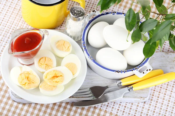 Boiled eggs on wooden board on tablecloth — Stock Photo, Image