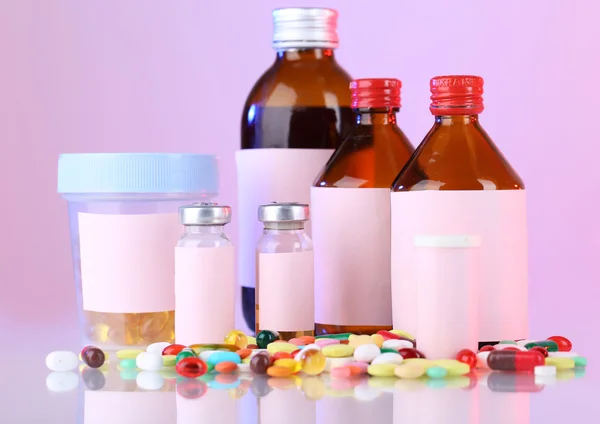 Píldoras y frascos de medicina sobre fondo rosa — Foto de Stock