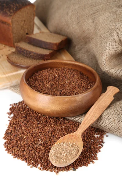 Buckwheat groats in bowl and wooden spoon closeup — Stock Photo, Image