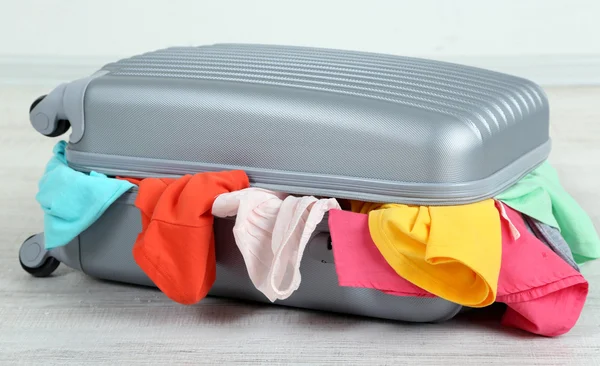 Suitcase with clothes on floor — Stock Photo, Image