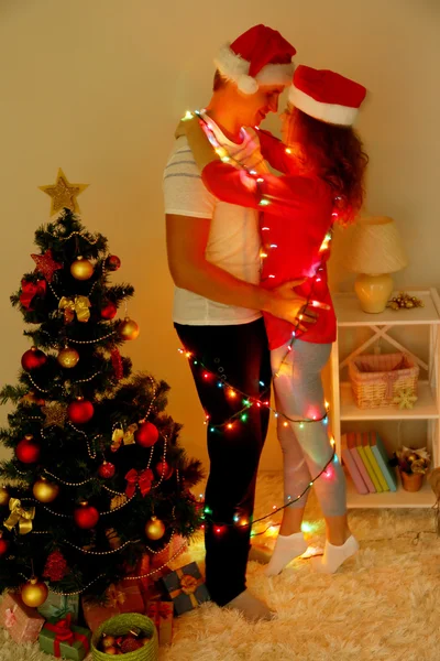 Feliz pareja joven cerca del árbol de Navidad en casa — Foto de Stock