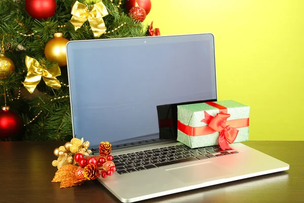 Laptop met geschenken op tafel op groene achtergrond — Stockfoto