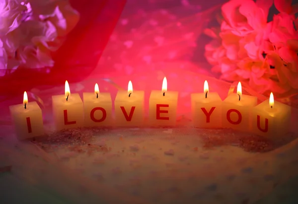 Svíčky s tištěnou znamení miluji tě, na pozadí barevných tkanin — Stock fotografie
