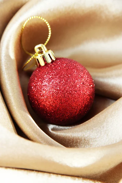 Schöne Weihnachtskugel auf goldenem Satintuch — Stockfoto