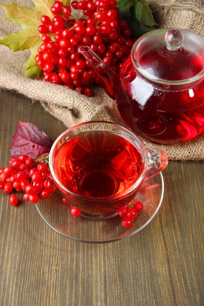 Bodegón con té de viburnum en servilleta de tela de saco, sobre fondo de madera — Stok fotoğraf