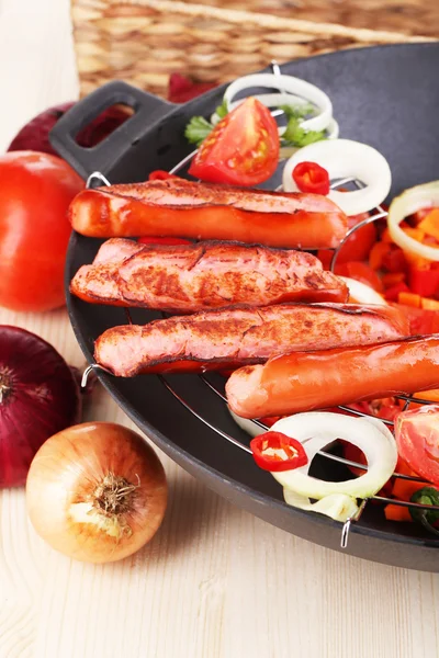 Delicious sausages with vegetables in wok on wooden table close-up — Stock Photo, Image