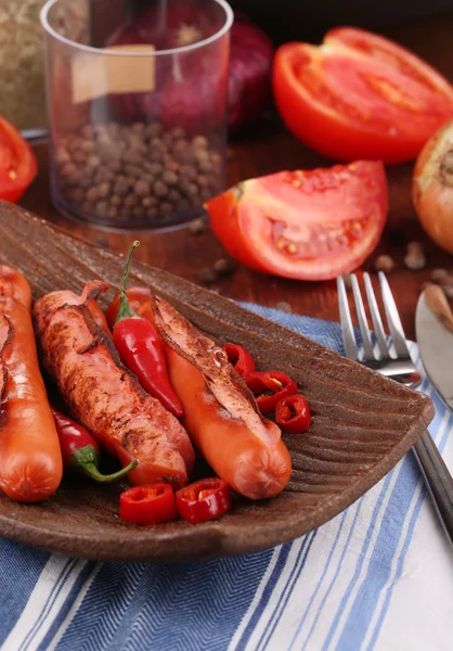 Deliciosas salchichas con verduras en plato sobre mesa de madera de cerca —  Fotos de Stock