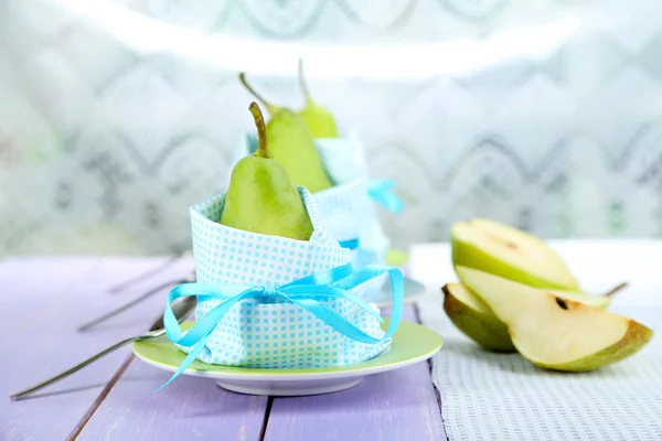 Päron i servetter på tallrikar på träbord på ljus bakgrund — Stockfoto