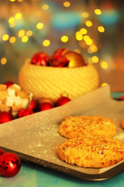 Процесс приготовления новогодних печенек на фоне рождественских огней — стоковое фото