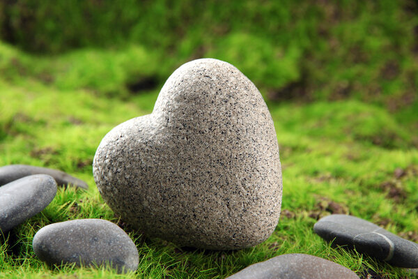 Grey stone in shape of heart, on grass background