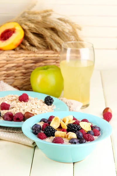 Haferflocken in Tellern mit Beeren auf Servietten auf Holztisch auf hellem Hintergrund — Stockfoto