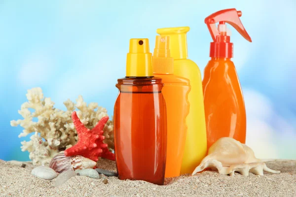 Botellas con crema bronceadora, sobre fondo azul — Foto de Stock