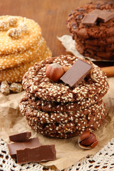 Homemade cookies with sesame seeds, chocolate, on napkin, on wooden background — Stock Photo, Image