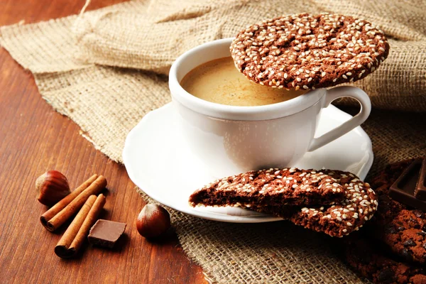 Xícara de café saboroso com biscoitos saborosos, em fundo de madeira — Fotografia de Stock