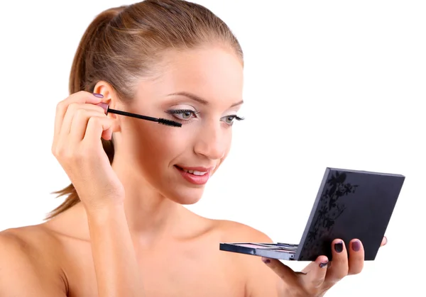 Beautiful girl paints eyelashes before small mirror isolated on white — Stock Photo, Image