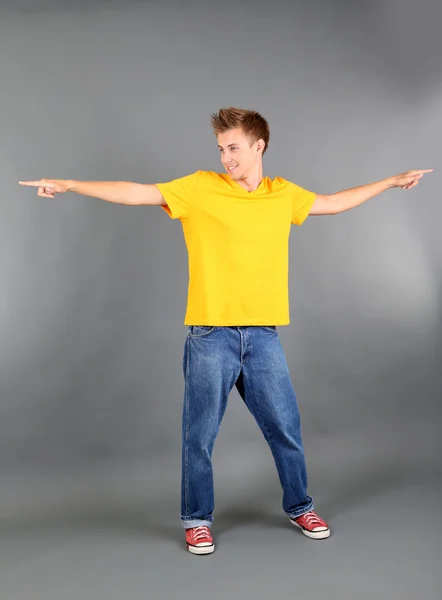 Handsome young man dancing on grey background — Stock Photo, Image