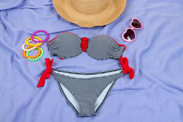 Costume da bagno e articoli da spiaggia su sfondo viola — Foto Stock